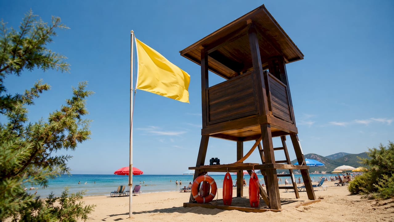 Torretta del bagnino con bandiera rossa su una spiaggia del Mediterraneo