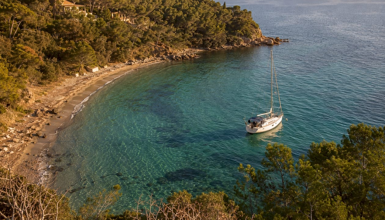 Una barca si gode la tranquillità della Baia di Viticcio, immersa in acque cristalline.